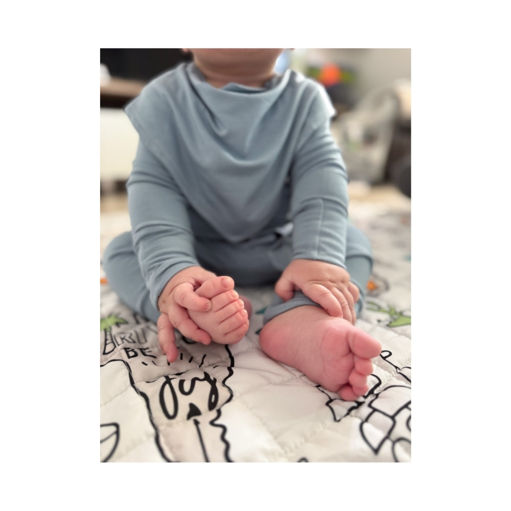 Baby wearing Birdie blue bamboo sleepsuit pyjama with magnetic closure and soft stretch and blue bib hypoallergenic