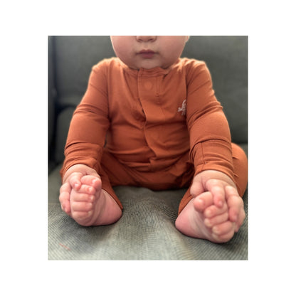 Baby wearing Birdie terracotta orange bamboo sleepsuit with magnetic closure and soft stretch