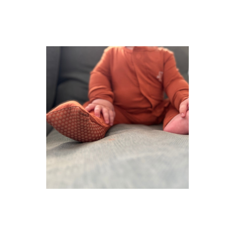 Baby wearing Birdie terracotta bamboo sleepsuit with magnetic closure and soft stretch and convertible footies
